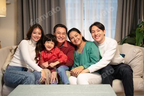 Preview: Portrait of Asian parents, child, and grandparents sitting on the sofa in the living room at home.