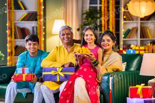 Preview: Indian family siutting with gift box on sofa on diwali festival night