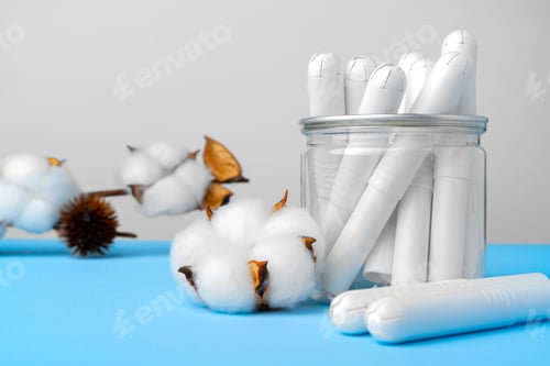 Preview: Female medical tampons and cotton flower on blue paper background