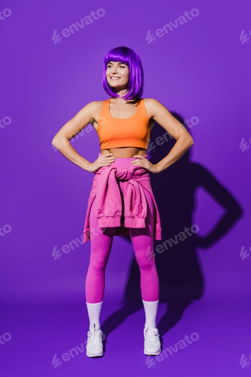 Preview: Cheerful woman wearing colorful sportswear sitting against purple background