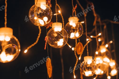 Preview: A beautiful creative garland of glass balls with glowing bulbs inside on a dark background.