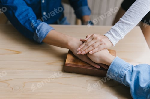 Preview: Friends holding hands on a book showing support and unity