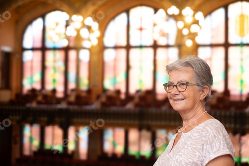 Preview: Elderly woman visiting the house of music in Barcelona. in the background the artistic stained glass