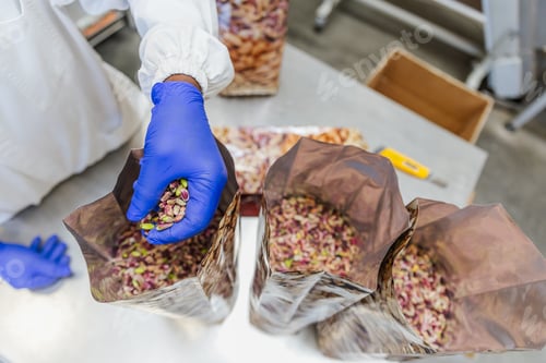 Preview: Close up of worker’s hand placing dry pistachios in bags from above