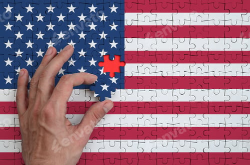 Preview: United States of America flag is depicted on a puzzle, which the man's hand completes to fold.