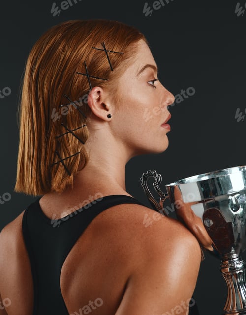 Preview: Studio shot of a sporty young woman holding a trophy against a black background