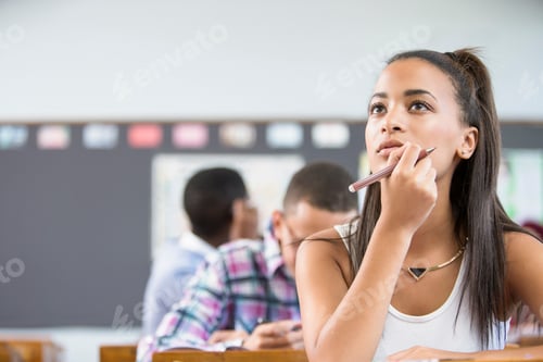 Preview: Female student, sitting at desk in classroom, thinking