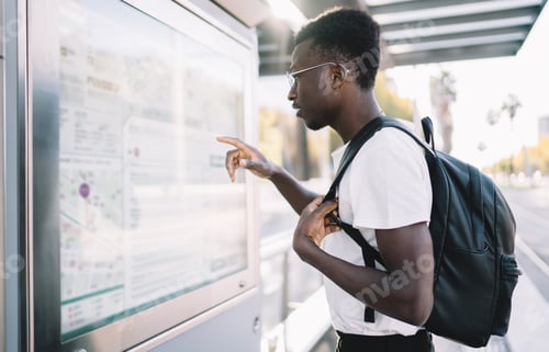 Preview: African American tourist with backpack looking at rout map