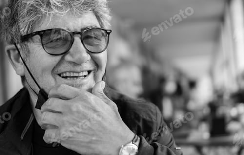 Preview: Grayscale shot of a senior Caucasian male wearing glasses taking off his mask
