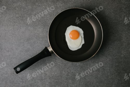 Preview: top view of frying pan with tasty fried egg on grey