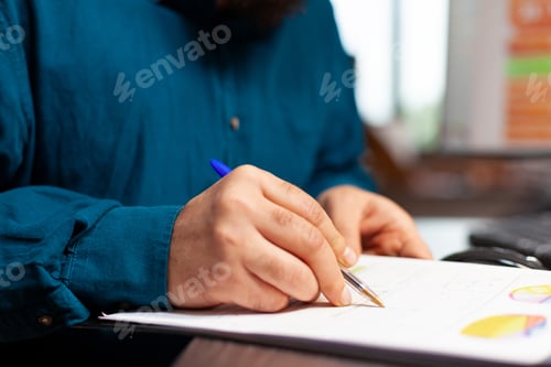 Preview: Closeup of entrepreneur hand sitting at table analyzing document with company plan
