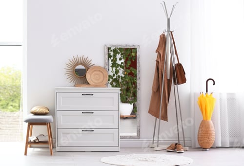 Preview: Modern hallway interior with chest of drawers and clothes on hanger stand. Space for text