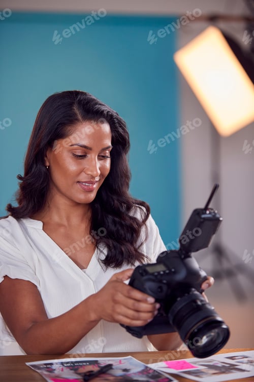 Preview: Mature Female Photographer Checking Images On Camera During Fashion Shoot In Studio
