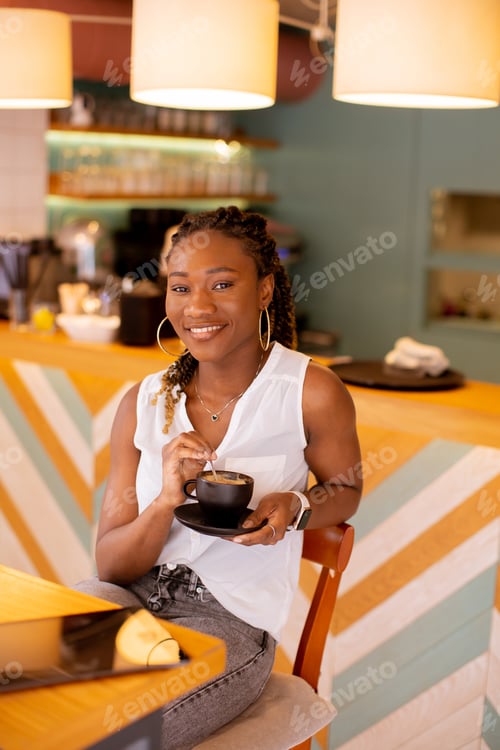 Preview: Young black woman drinking coffee in the cafe