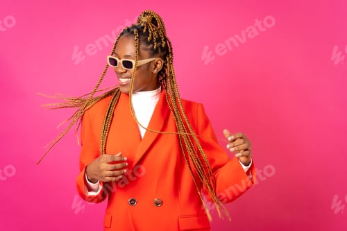 Preview: African young woman with braids on a pink background, in a red outfit having fun