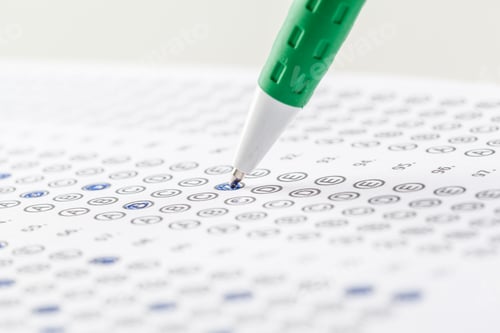 Preview: Student fills in answers on a test sheet with a green pen during a classroom session