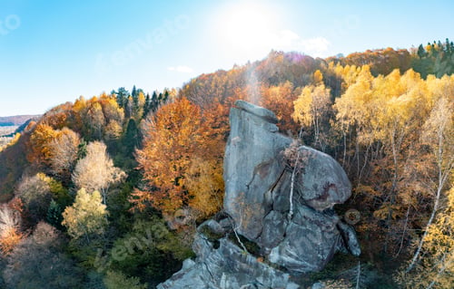 Preview: Huge rock in autumn mountain forest at bright sunlight