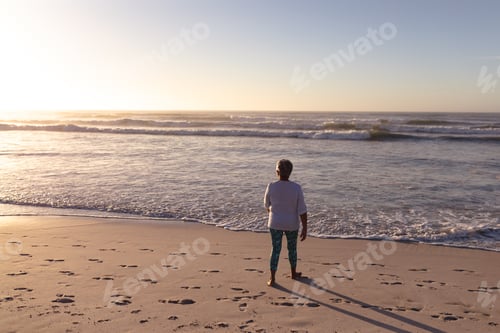 Preview: Rear view of senior african american woman walking on the beach