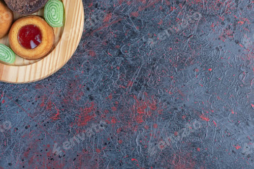 Preview: Various cakes and marmalades on a wooden platter on abstract background