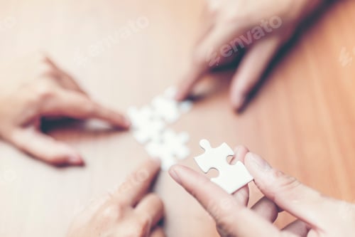 Preview: High Angle View Of Businesspeople Hand Solving Jigsaw Puzzle On Wooden Desk