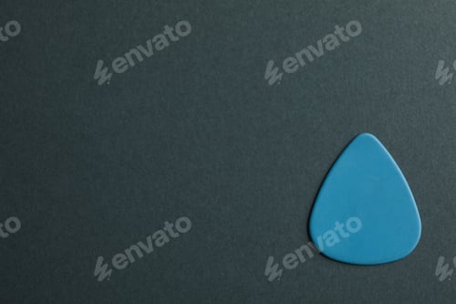 Preview: Blue guitar pick on dark background, space for text