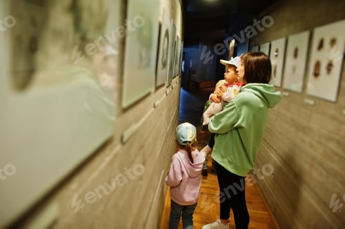 Preview: Mother with children exploring expositions in museum halls.