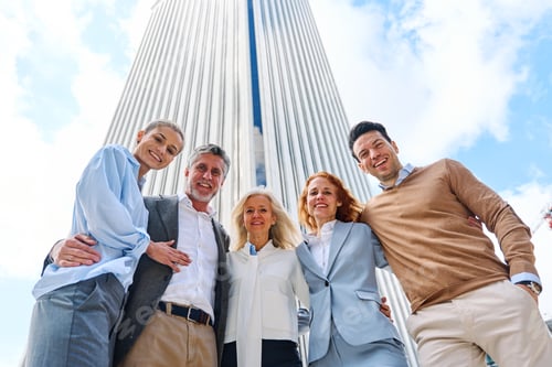 Preview: Business people embracing while looking at camera outdoors