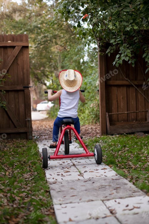 Preview: Four year old girl riding her tricycle out of garden gate