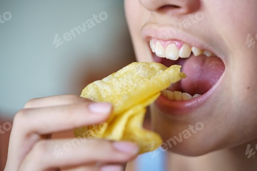 Preview: Unrecognizable teenage girl eating crunchy potato chips at home