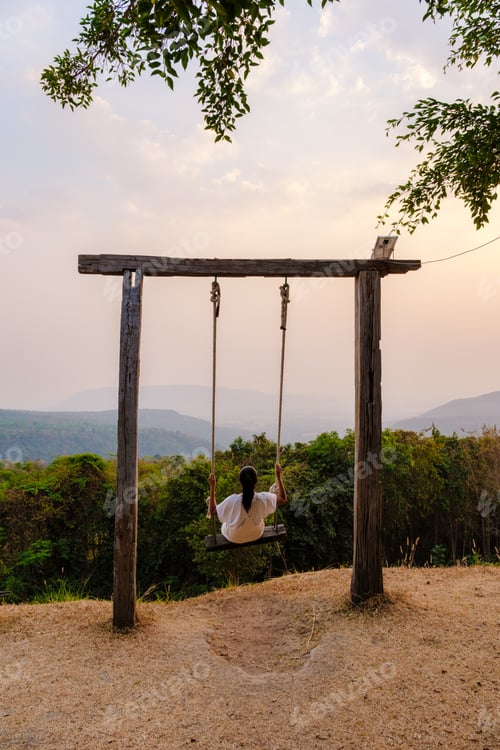 Preview: Asian women in a swing at Sunset at a mountain camping in Phitsanulok Thailand