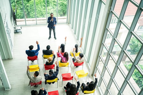 Preview: Raised up hands of large group in seminar class room to agree with speaker at conference seminar