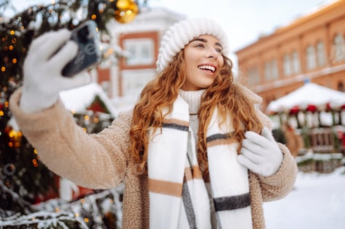 Preview: Happy woman drinking hot drink and taking selfie on winter snowy day. Weekend concept.