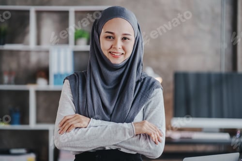 Preview: Portrait of a Muslim business woman happily looking at the camera in a hijab at work. smiling arab w