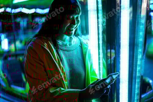 Preview: Happy asian girl using mobile phone at amusement park - Focus on face