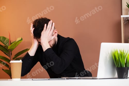 Preview: Frustrated young business man working on laptop at office