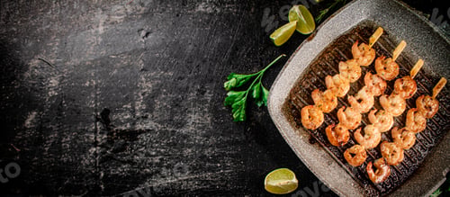 Preview: Grilled shrimp in a frying pan with parsley and pieces of lime.