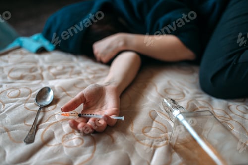 Preview: Female druggy with syringe in hand lies in bed