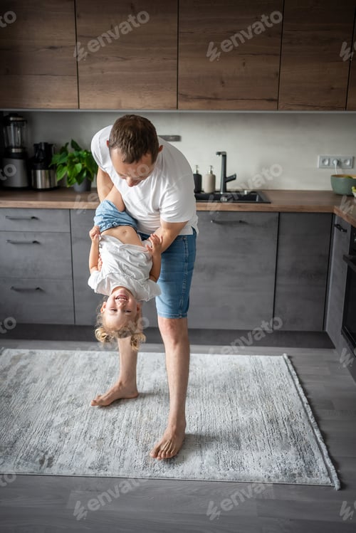 Preview: A happy father and little girl joyfully spending time in a modern kitchen. Happy family. Father's