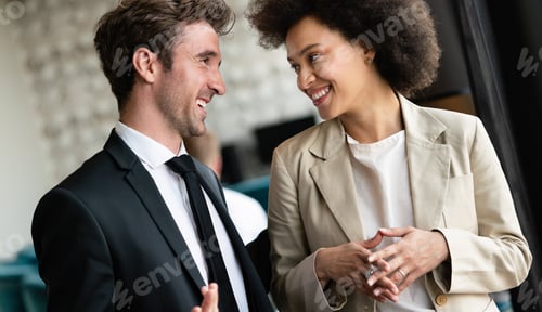 Preview: Two cheerful business people discussing something and smiling in office