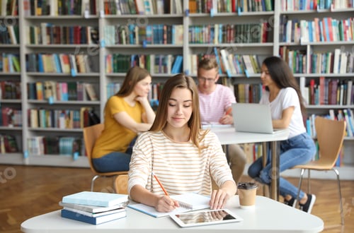 Preview: Young woman studying at table in library