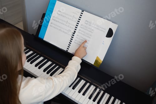 Preview: Young girl learning to play piano while reading music from a sheet