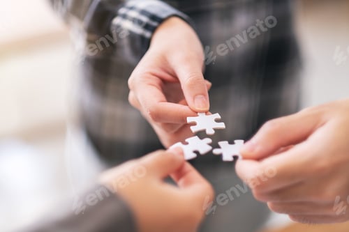 Preview: Closeup image of many people hands holding and putting a piece of white jigsaw puzzle together