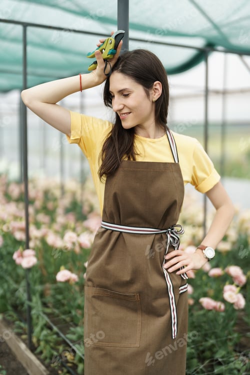 Preview: Pretty woman working with flowers in the green house