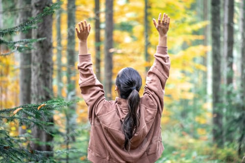 Preview: Woman on a blurred background of the autumn forest, view from the back.