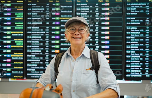 Preview: Happy senior woman in airport looking at camera while check her flight departure gate on timetable