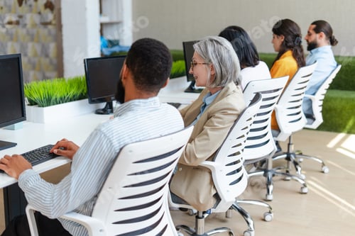 Preview: Diverse team of professionals working on computers in modern office