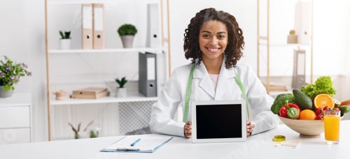Preview: Smiling black nutritionist demonstrating digital tablet with empty screen