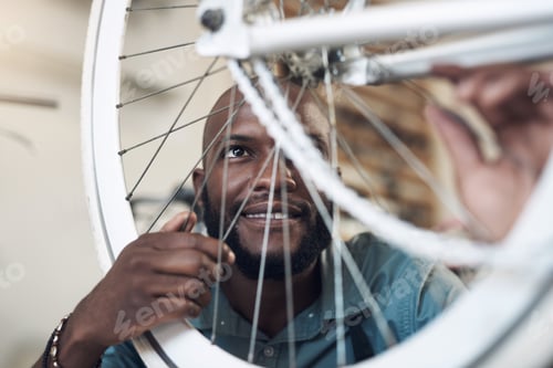 Preview: Shot of a handsome young man crouching alone in his shop and repairing a bicycle wheel