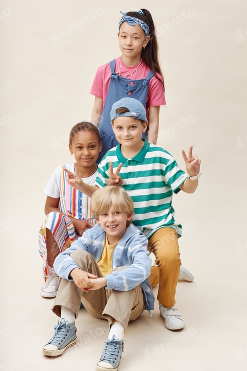 Preview: Multiethnic Group of Four Smiling Kids Showing V Sign Posing Together in Studio