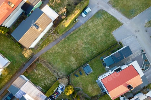 Preview: Aerial view of residential houses with red roofs and streets with parked cars in rural town area
